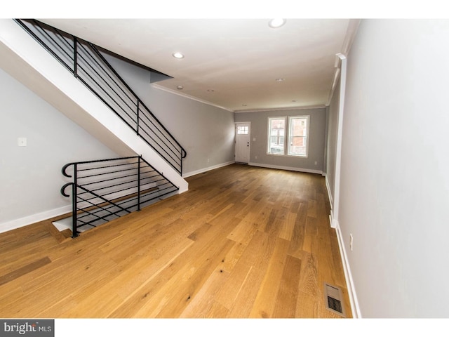 spare room with wood finished floors, visible vents, baseboards, recessed lighting, and crown molding