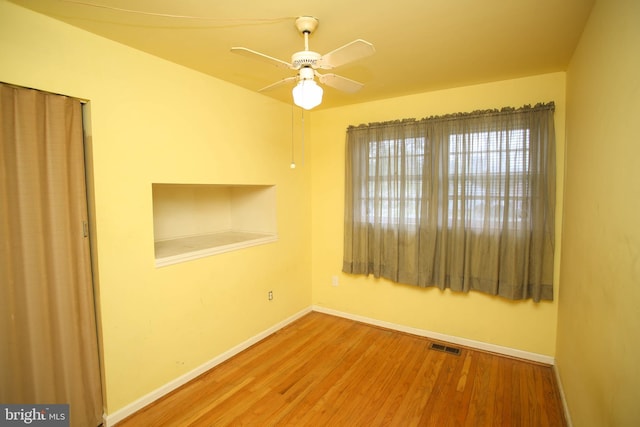 empty room with visible vents, baseboards, a ceiling fan, and wood finished floors