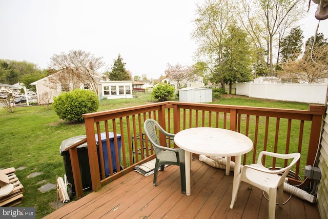 deck with a storage shed, an outbuilding, fence, a yard, and outdoor dining area