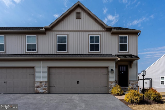 view of front of house with stone siding, an attached garage, and driveway