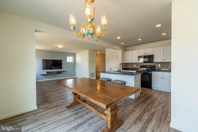 unfurnished dining area featuring a sink, visible vents, wood finished floors, and a chandelier