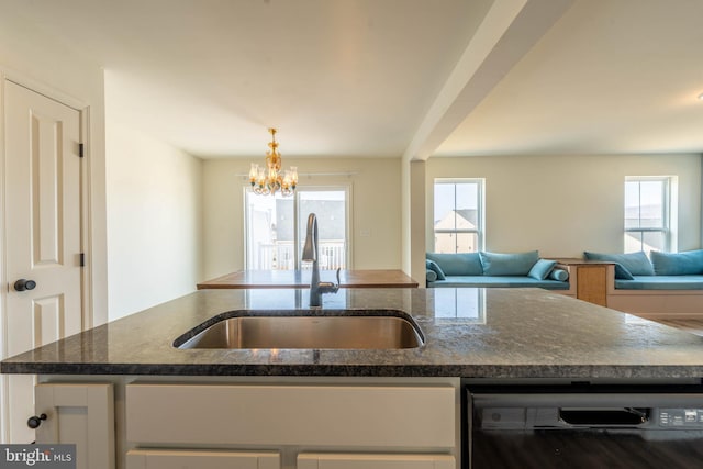 kitchen with a healthy amount of sunlight, open floor plan, black dishwasher, dark stone countertops, and a sink