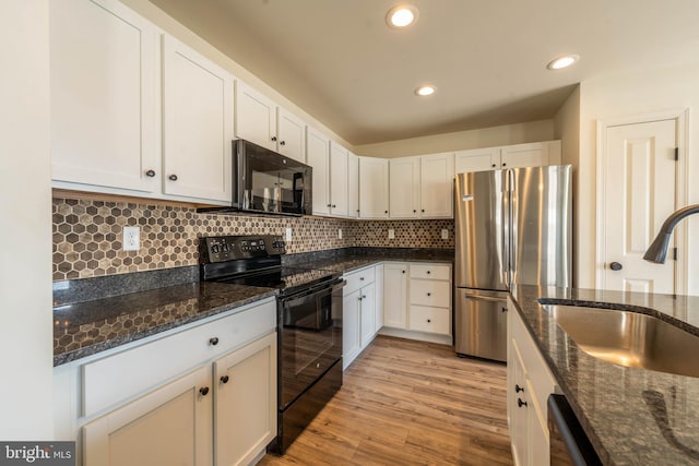 kitchen with light wood finished floors, a sink, black appliances, white cabinets, and tasteful backsplash