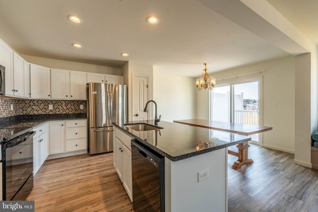 kitchen featuring a sink, black appliances, white cabinets, light wood-style floors, and tasteful backsplash