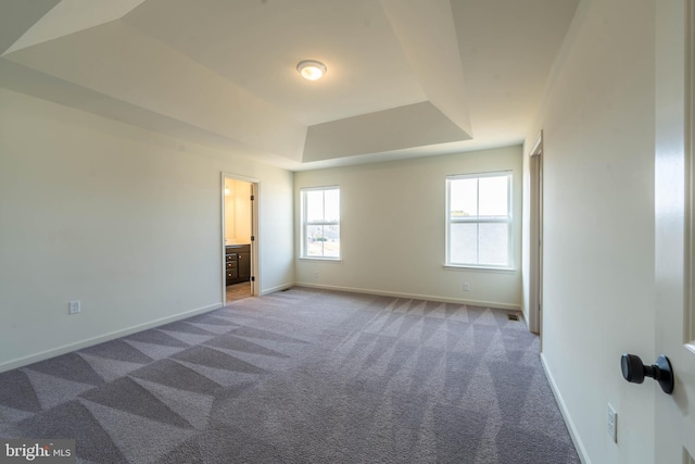 unfurnished bedroom with a raised ceiling, baseboards, and carpet floors