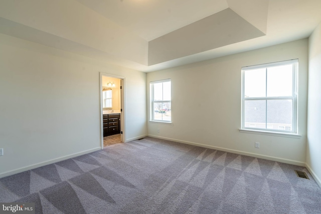 unfurnished room with visible vents, baseboards, carpet, and a tray ceiling