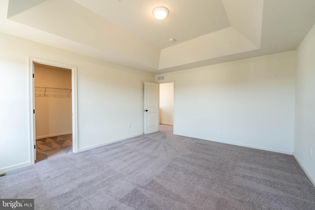 unfurnished bedroom with a raised ceiling and carpet