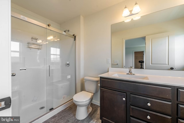 bathroom featuring vanity, toilet, wood finished floors, and a stall shower