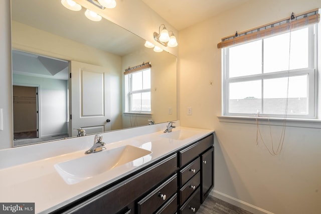 full bath with double vanity, baseboards, and a sink