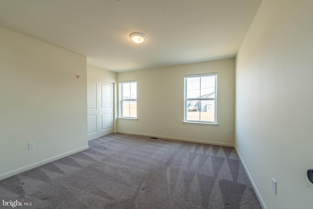 spare room with baseboards and carpet floors