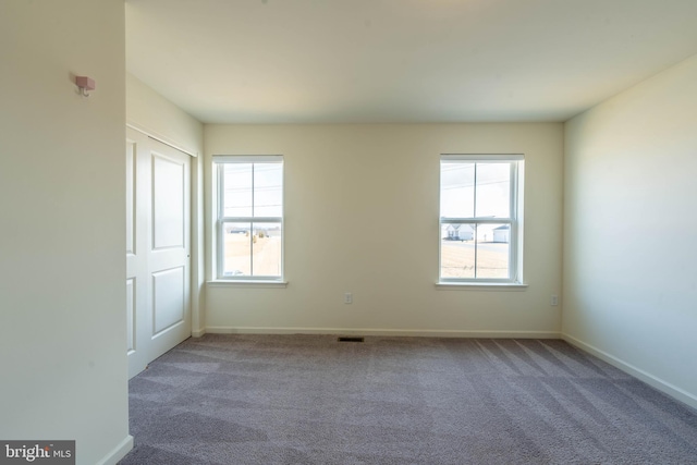 carpeted spare room with plenty of natural light, visible vents, and baseboards