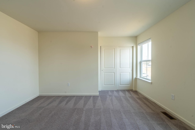 carpeted spare room featuring visible vents and baseboards