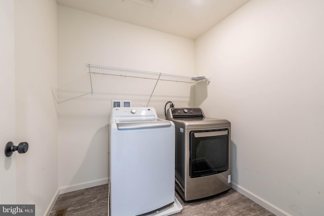 washroom featuring laundry area, wood finished floors, baseboards, and washer and clothes dryer