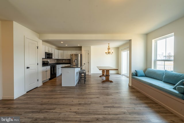 kitchen featuring black appliances, a breakfast bar, dark countertops, open floor plan, and a chandelier