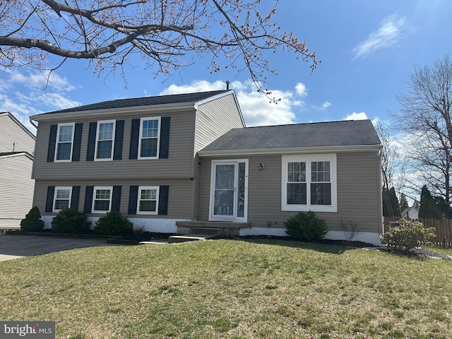 tri-level home featuring a front yard and fence