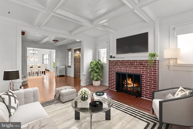 living area with a chandelier, radiator heating unit, a fireplace, wood finished floors, and coffered ceiling