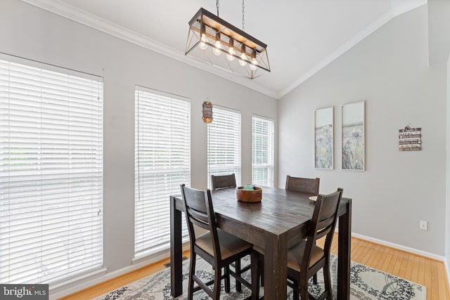 dining space featuring light wood finished floors, an inviting chandelier, crown molding, baseboards, and vaulted ceiling