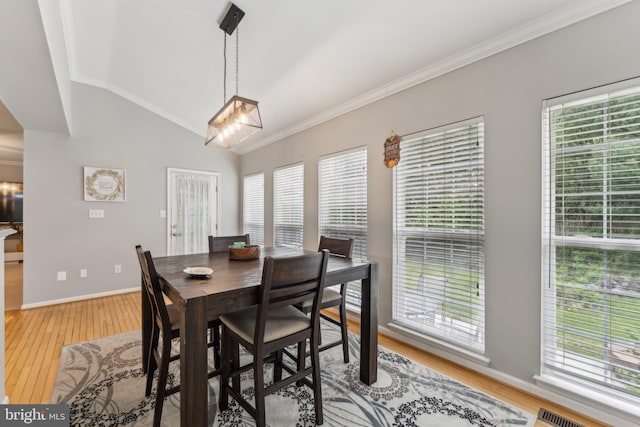 dining space featuring crown molding, an inviting chandelier, a wealth of natural light, and light wood finished floors