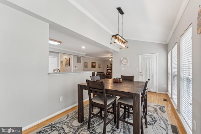 dining area with ornamental molding, light wood-type flooring, visible vents, vaulted ceiling, and ceiling fan
