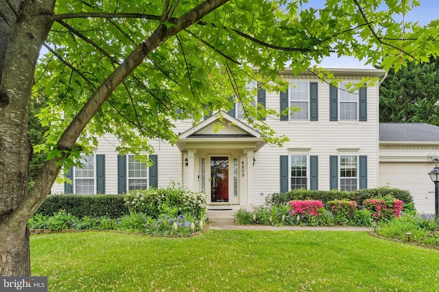 colonial house featuring an attached garage and a front yard