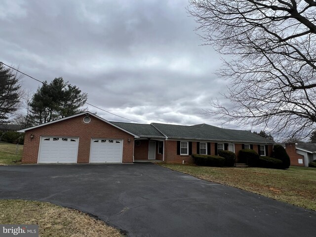 single story home with aphalt driveway, an attached garage, brick siding, and a front lawn