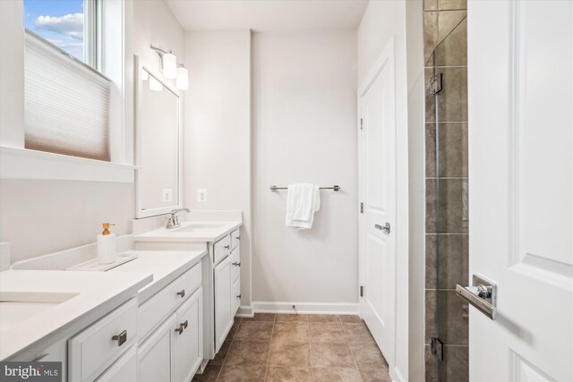 bathroom featuring a tile shower, vanity, baseboards, and tile patterned flooring