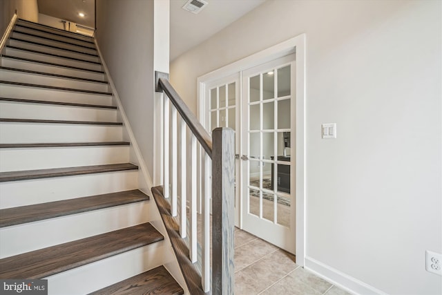 stairs with tile patterned floors, visible vents, and baseboards