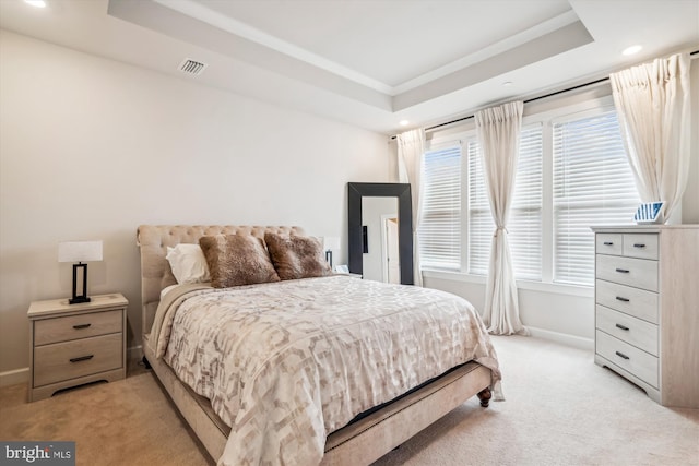bedroom featuring light carpet, visible vents, a tray ceiling, and baseboards