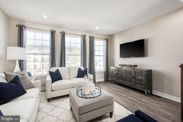 living area with plenty of natural light, recessed lighting, baseboards, and wood finished floors