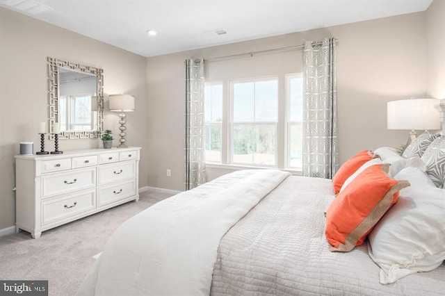 bedroom featuring visible vents, light colored carpet, and baseboards