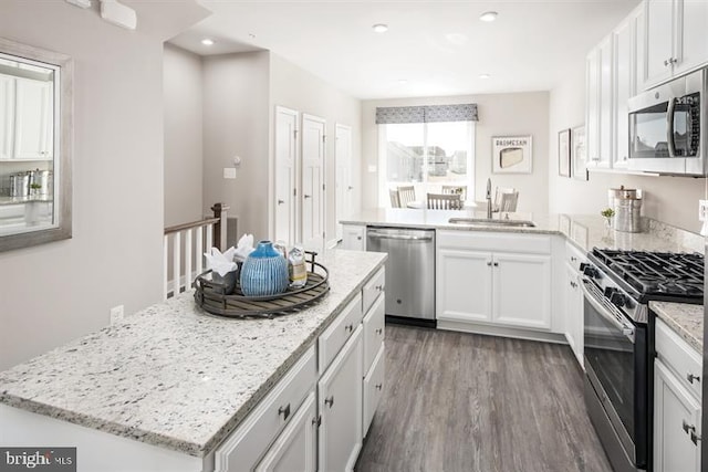 kitchen featuring a sink, stainless steel appliances, wood finished floors, and white cabinetry