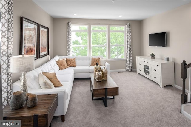 living area featuring baseboards and light carpet