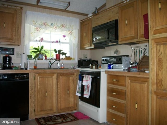 kitchen featuring brown cabinetry, a sink, decorative backsplash, black appliances, and light countertops