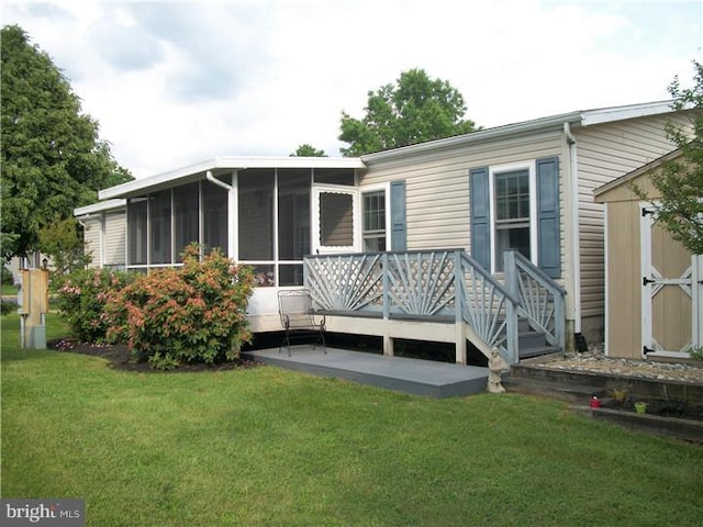 back of house with a sunroom, an outbuilding, a lawn, and a shed