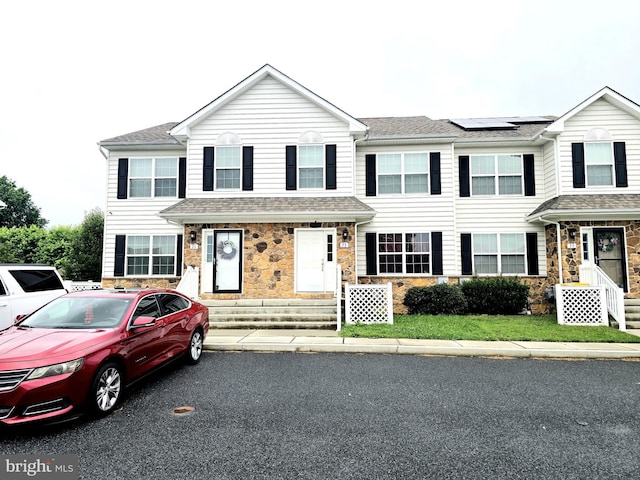 73 Toscano Dr, Smyrna, DE 19977 - townhome / multi-family property with stone siding, solar panels, and roof with shingles