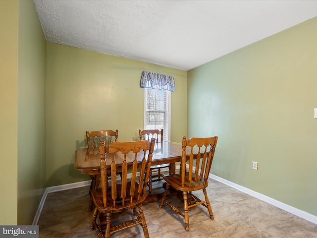 dining area with a textured ceiling and baseboards