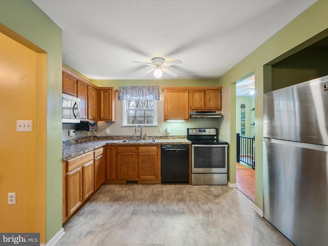 kitchen featuring ceiling fan, under cabinet range hood, a sink, stainless steel appliances, and brown cabinets