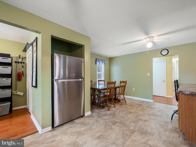 kitchen featuring baseboards, freestanding refrigerator, and ceiling fan