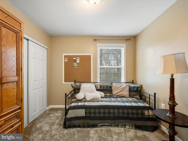 bedroom with a closet, carpet flooring, baseboards, and a textured ceiling