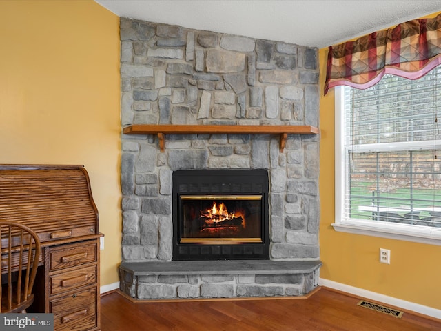 room details featuring visible vents, baseboards, wood finished floors, and a fireplace