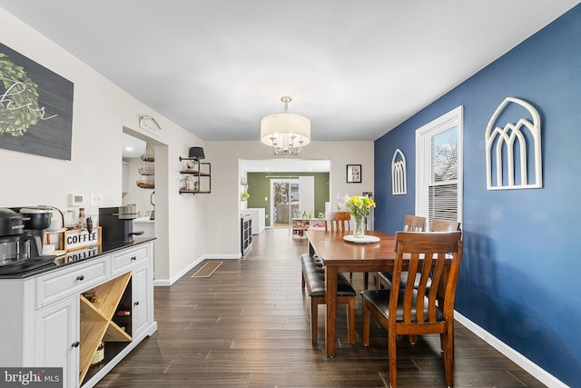 dining space with dark wood finished floors, baseboards, and an inviting chandelier