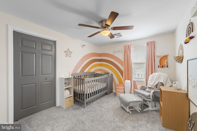 bedroom with visible vents, a crib, carpet floors, and a ceiling fan