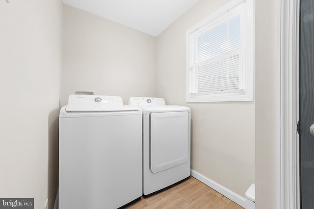 washroom featuring laundry area, washing machine and dryer, light wood-style flooring, and baseboards