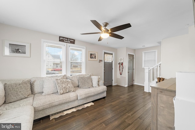 living room with baseboards, stairs, ceiling fan, and dark wood-style flooring