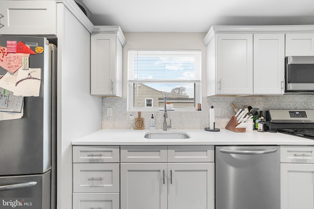 kitchen featuring a sink, backsplash, white cabinetry, appliances with stainless steel finishes, and light countertops