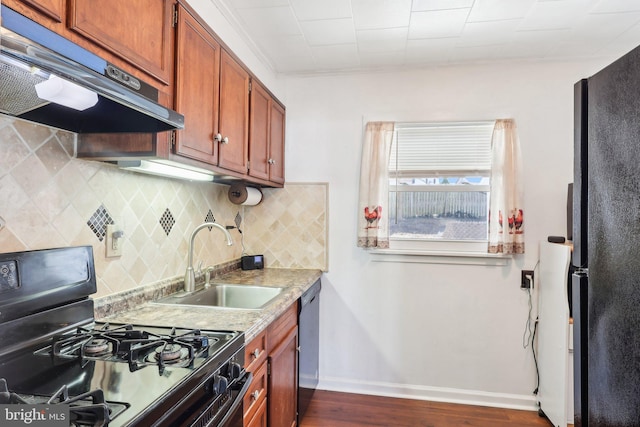 kitchen with light countertops, baseboards, under cabinet range hood, a sink, and black appliances