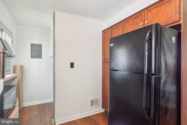 kitchen with visible vents, brown cabinetry, wood finished floors, and freestanding refrigerator