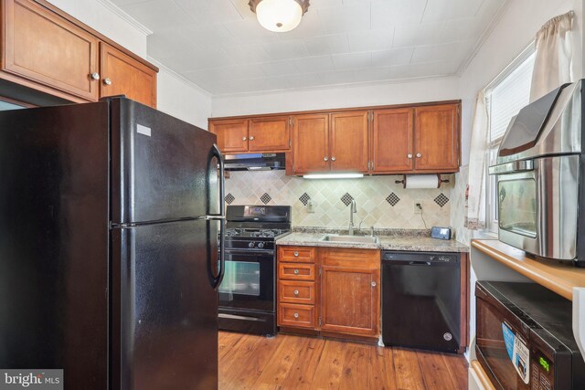 kitchen featuring a sink, under cabinet range hood, black appliances, and crown molding
