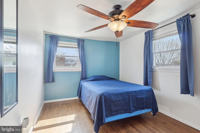 bedroom with baseboards, multiple windows, and wood finished floors