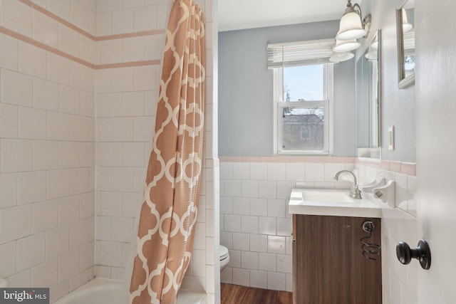 full bath with vanity, shower / tub combo, tile walls, toilet, and a wainscoted wall